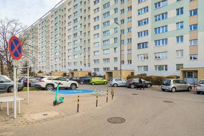 Un espace de stationnement avec un immeuble résidentiel à plusieurs étages en arrière-plan.