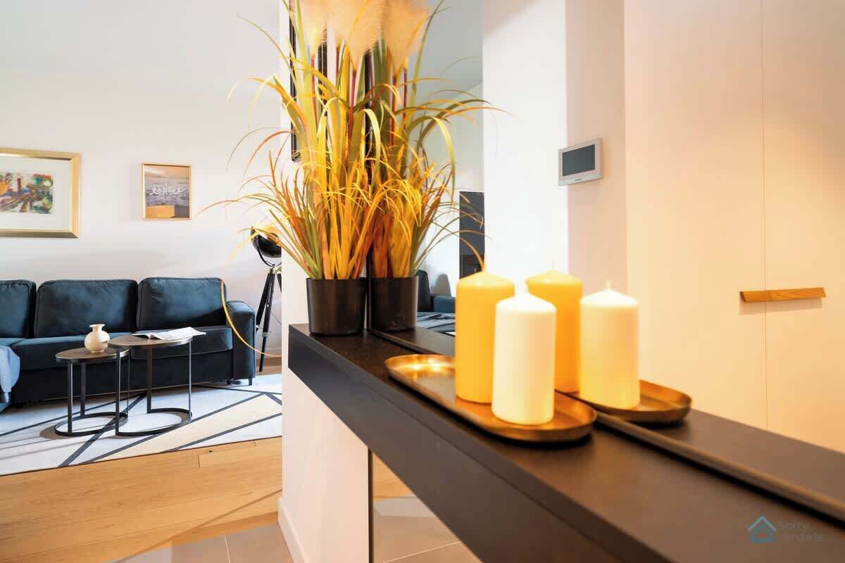 A modern living room with a dark sofa, a small side table, and a large potted plant.