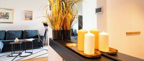 A modern living room with a dark sofa, a small side table, and a large potted plant.