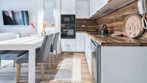 A modern kitchen with white cabinetry, a built-in oven, a microwave, and a coffee maker.