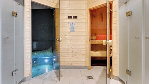 A sauna room with a tiled floor, wooden benches, and a door with a sign indicating sauna use.