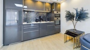Una cocina moderna con armarios oscuros, salpicadero de azulejos y electrodomésticos integrados.