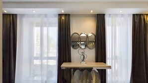 Un comedor moderno con una mesa de madera, cortinas oscuras y un espejo montado en la pared.