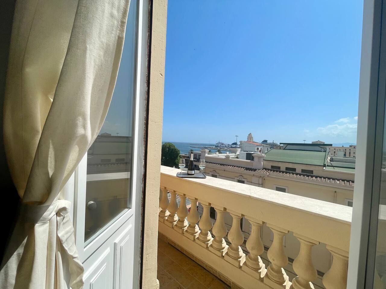 A balcony with a view of a coastal cityscape, including buildings and a body of water.