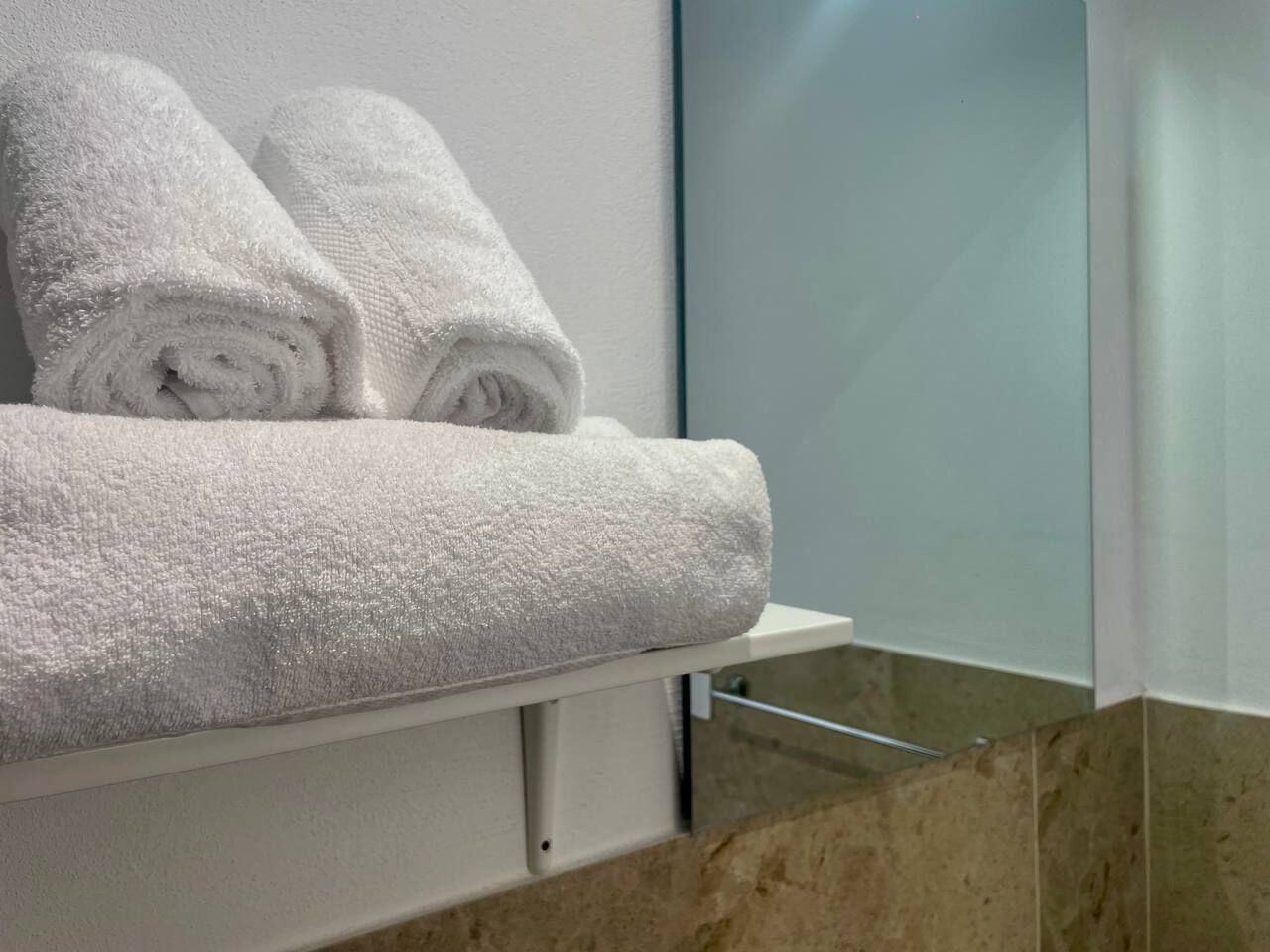 A bathroom with a towel rack holding two neatly folded white towels.