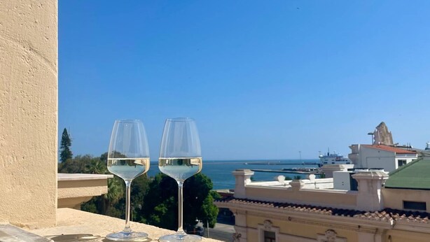 Dos copas de vino blanco en un balcón con vistas a la costa.