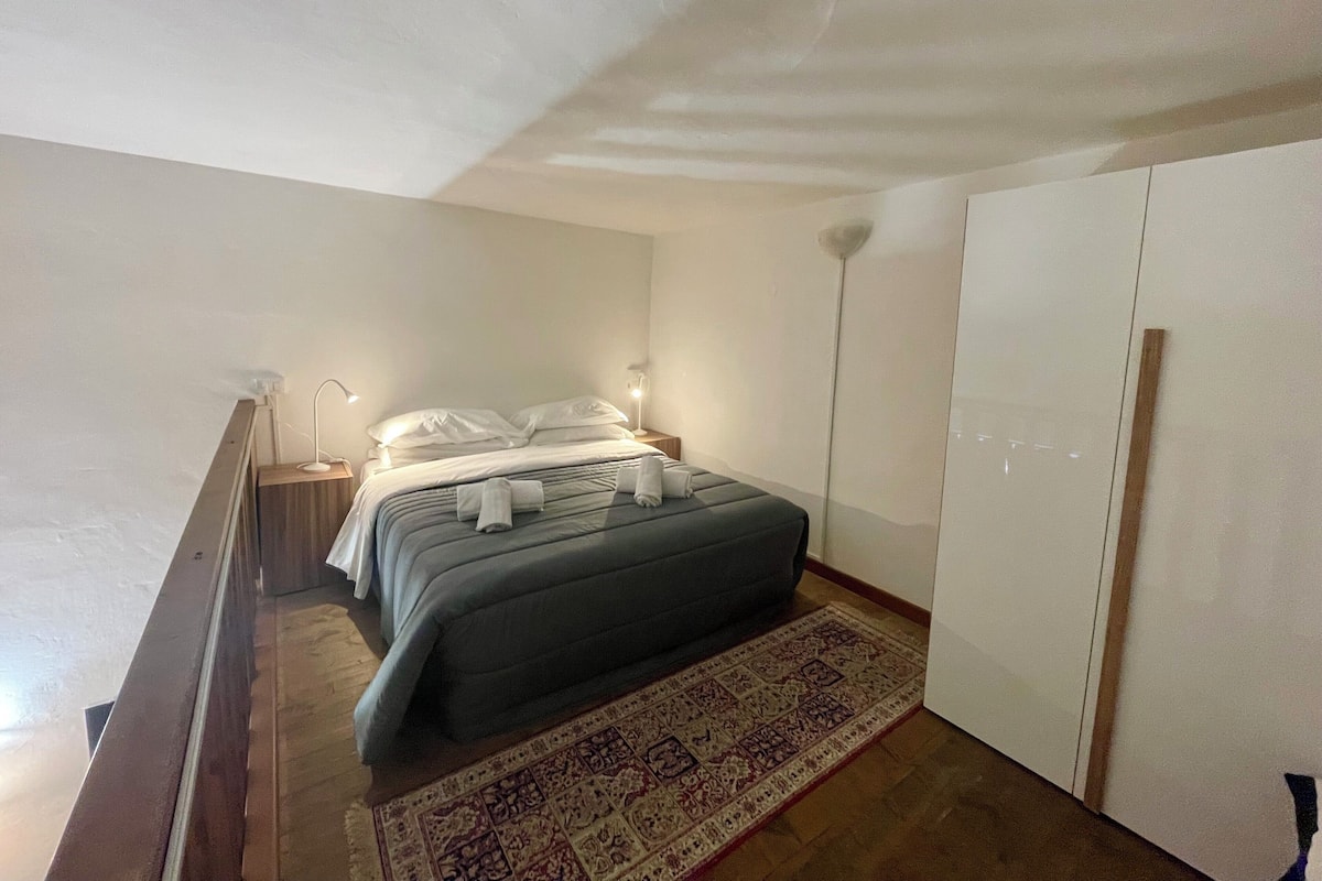 Quarto com cama, abajures, guarda-roupa e tapete estampado.