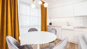 A modern kitchen with white cabinets, a round dining table, and a pendant light.