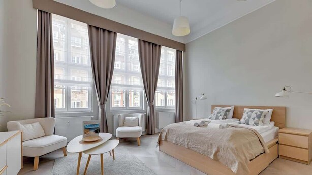 Een moderne slaapkamer met een bed, nachtkastjes, een bank, een kleine tafel en een stoel.