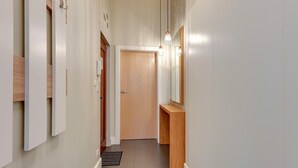 Een hal met een houten deur, een bankje en een spiegel aan de muur.