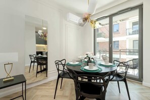 Un espace repas moderne avec une table ronde, des chaises noires et une vue sur le balcon extérieur.
