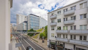 Eine moderne Stadtstraße mit einer Fußgängerbrücke, einem Auto und Gebäuden mit Balkonen und Geschäften.