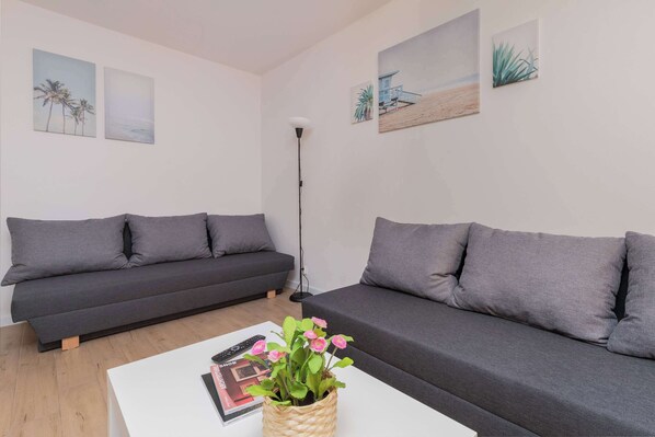 A modern living room with two grey sofas, a white coffee table, and a floor lamp.