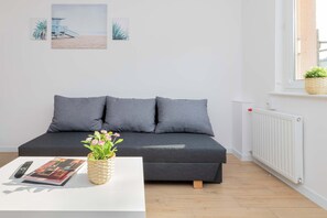 A modern living room with a grey sofa, a white coffee table, and a remote control.