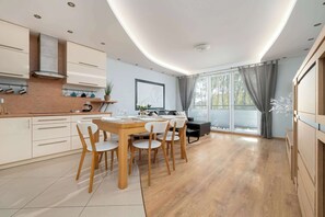 Une cuisine moderne avec un coin repas, des meubles en bois et une grande fenêtre avec des rideaux.