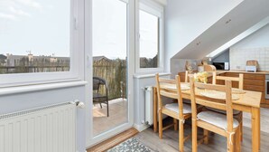 A modern kitchen with wooden cabinets, a dining table with chairs, and a view of the outside.