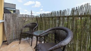 An outdoor patio with wicker furniture and a bamboo fence.
