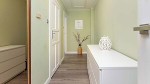 A hallway with a wooden floor, a white door, and a white counter with a decorative lantern.