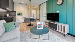 Un salon moderne comprenant un canapé, une table basse, un téléviseur et un coin cuisine.