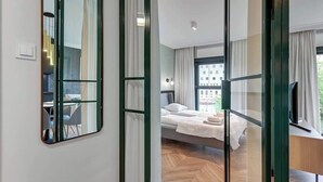 Une chambre d’hôtel moderne équipée d’un lit, d’un bureau, d’une chaise, d’un miroir et offrant une vue sur l’extérieur.