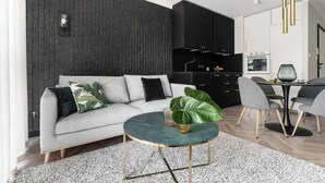 Una sala moderna con un sofá gris, una mesa de centro redonda y una pared de acento oscura.