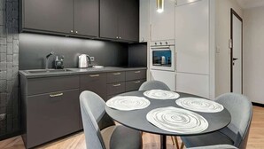 Una cocina moderna con armarios oscuros, horno empotrado y una mesa redonda con cuatro sillas.