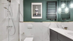 Un baño moderno con ducha acristalada, inodoro, lavamanos y un cuadro en la pared.