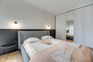 Et moderne hotelværelse med en stor seng, et natbord, et garderobeskab og et spejl.