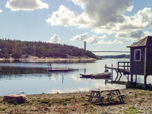 Vista del lago con un muelle, una mesa de picnic y una cabaña pequeña.