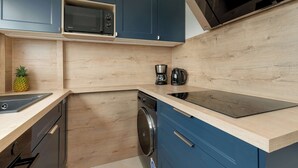 A modern kitchen with wooden cabinetry, a built-in microwave, a coffee maker, and a dishwasher.