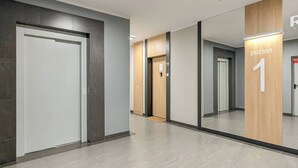 Een moderne hal met een spiegelwand, een houten accentmuur en een bordje met de tekst 'pozion 1'.