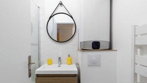 A modern bathroom with a white sink, wooden cabinet, and a round mirror. - Dify City - Charpennes (Villeurbanne)