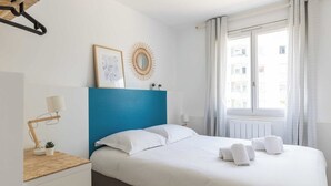 A hotel room with a bed, a desk, a lamp, a small plant, and a window with curtains. - Dify City - Charpennes (Villeurbanne)