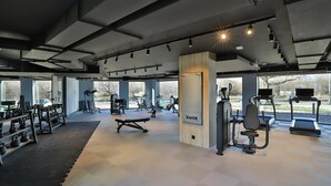Un gimnasio moderno con diverso equipamiento de ejercicio, amplias ventanas y un diseño limpio y espacioso.