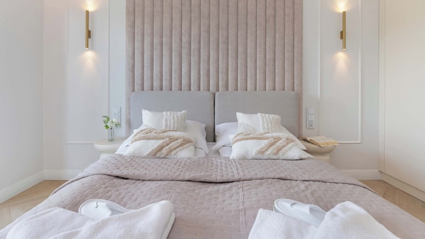 Un dormitorio moderno con una cama grande, dos mesitas de noche y una lámpara fijada a la pared.