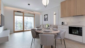Una cocina moderna con una mesa redonda, sillas grises y un ventanal grande.