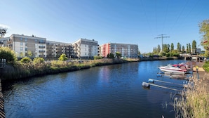 Un río con barcos amarrados a la derecha, rodeado de edificios modernos y vegetación.