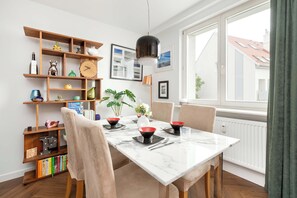 Un comedor con una mesa de mármol, sillas y una estantería de madera con diversos objetos.