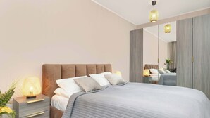 Un dormitorio moderno con una cama grande, una mesita de noche con lámpara y un espejo en la pared.