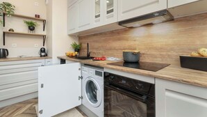 Una cocina moderna con armarios blancos, encimera de madera, lavadora integrada y estufa.