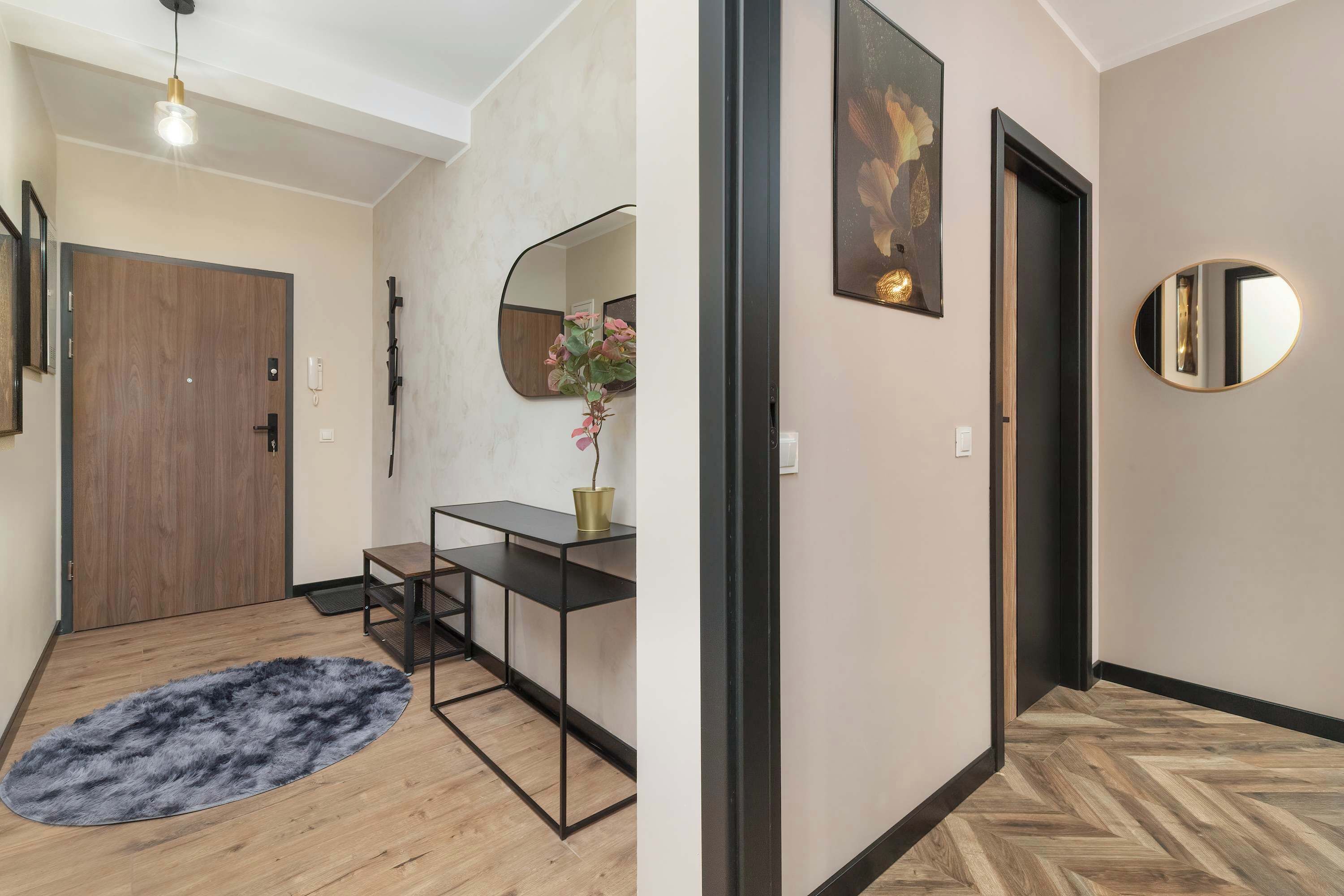 A hallway with a wooden door, a black-framed mirror, and a round mirror on the wall.