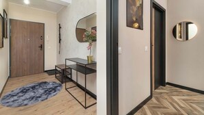 Un pasillo con una puerta de madera, un espejo con marco negro y un espejo redondo en la pared.