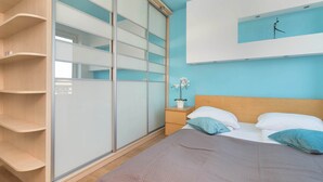 Ein Schlafzimmer mit einem Bett, einem Nachttisch, einer Topfpflanze und einem Schiebetürenschrank.