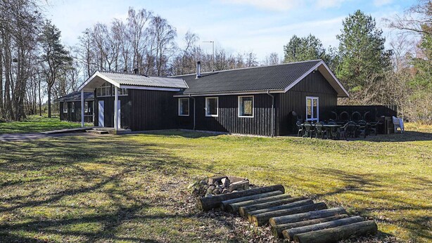 A black building with a sloped roof, a covered porch, and a small outdoor seating area with tables and chairs. - 2 Person Holiday Park Home in Laeso (Læsø)