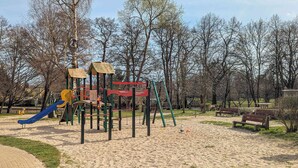 Un parque infantil con tobogán, estructuras para escalar y una zona de arena.