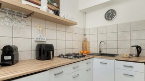 Una cocina moderna con armarios blancos, encimera de madera, estufa a gas, cafetera y lavabo.