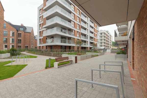 A view of the apartment complex, showcasing modern buildings and landscaped outdoor spaces. The design is contemporary and appealing.