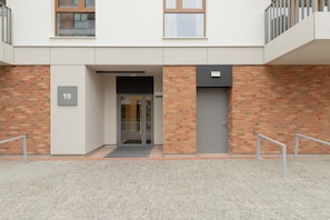 Une entrée moderne, avec une porte en verre, un mur en briques et une rambarde en métal.