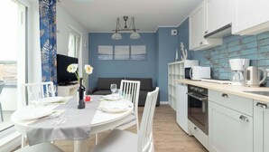 A modern kitchen with white cabinets, a built-in oven, and a dining area with a table set for two.