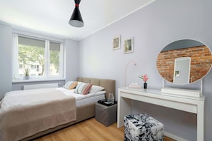 Un dormitorio con cama, mesita de noche, espejo y ventana.